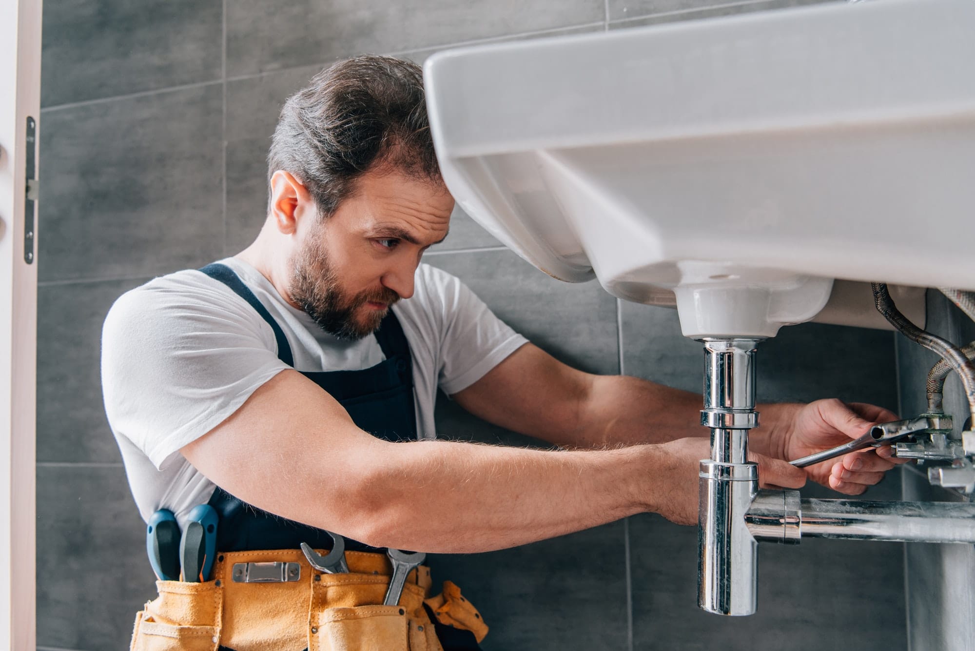 Male plumber working in fixing sink in bathroom